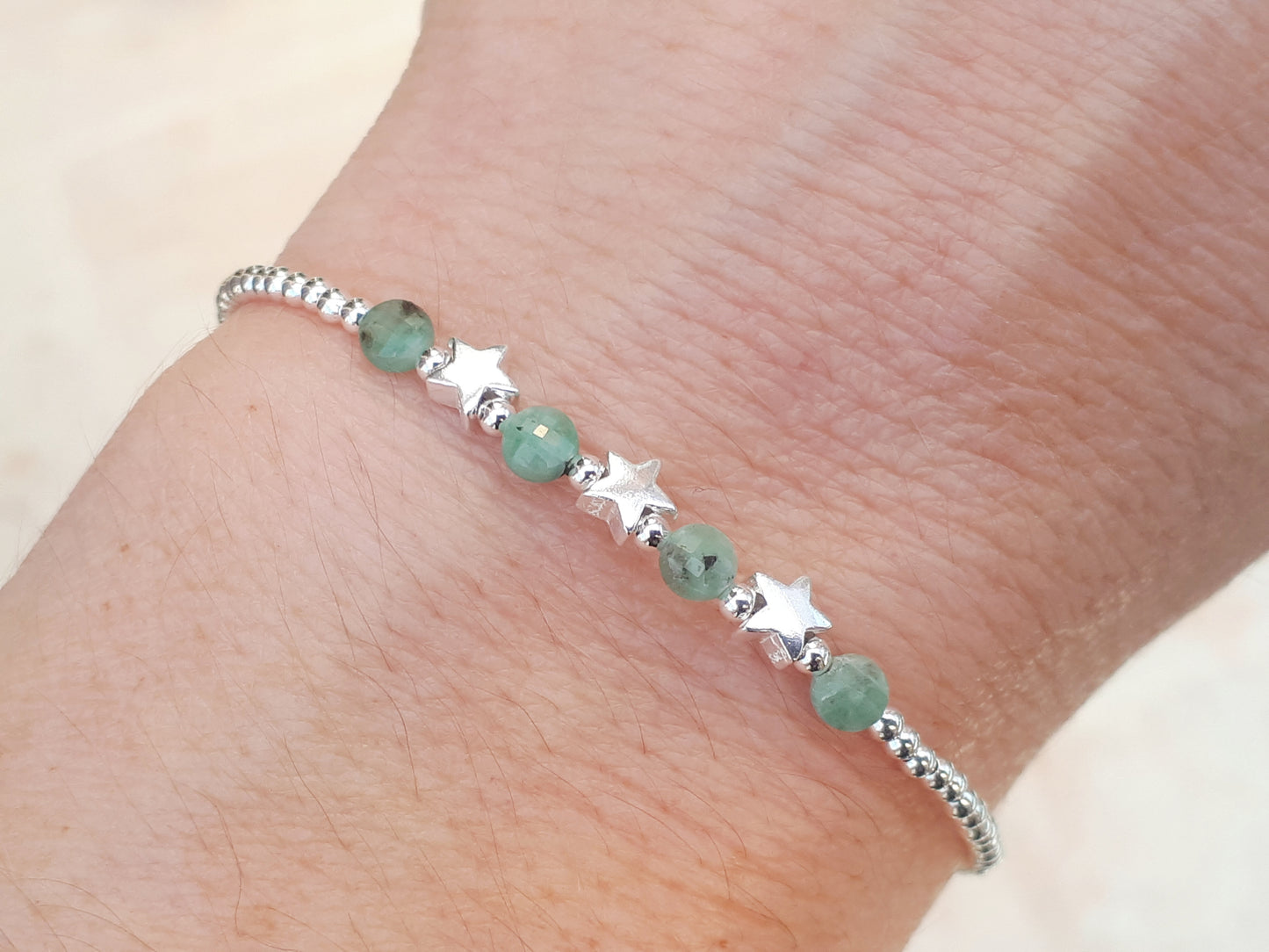 Silver star bracelet with emerald gemstones.