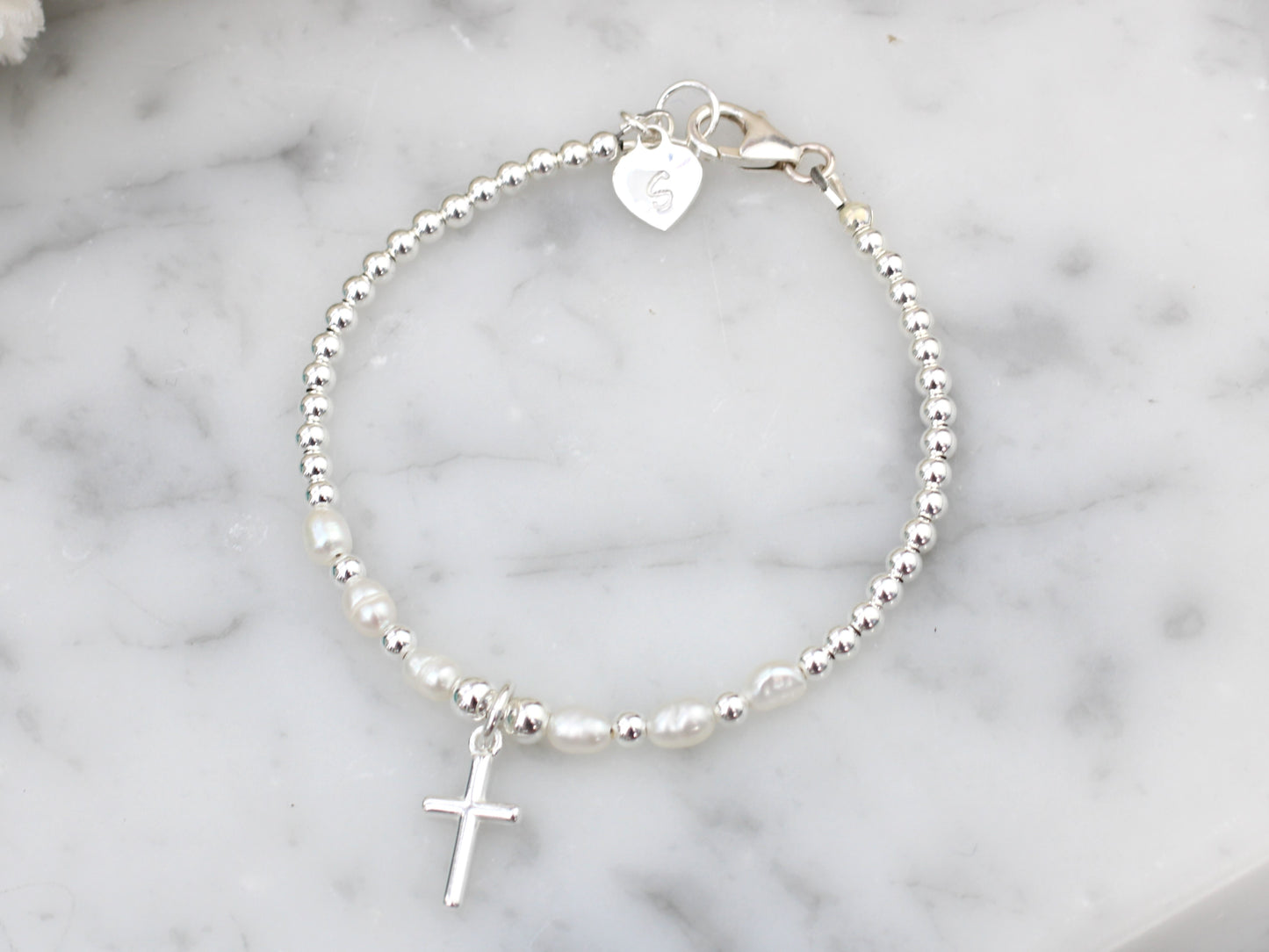 Cross charm bracelet with freshwater pearls.