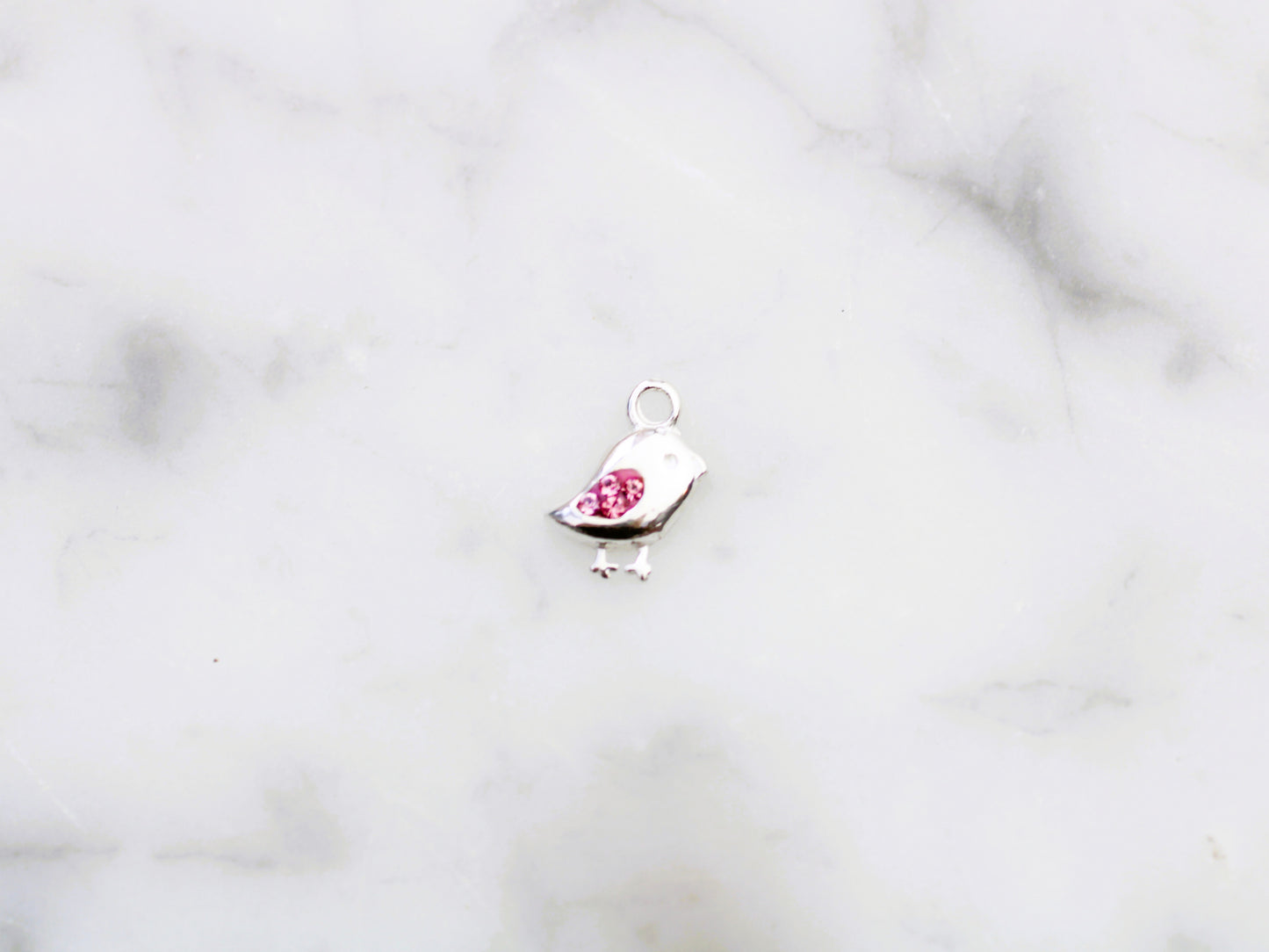Bird charm with pink crystals.