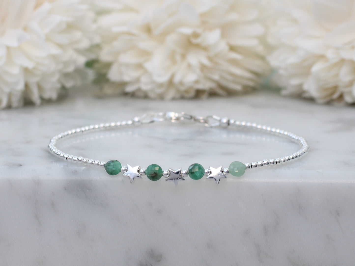 Silver star bracelet with emerald gemstones.