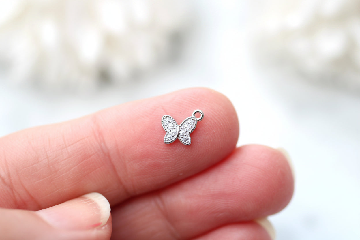 Silver butterfly charm on a finger with a blurred background