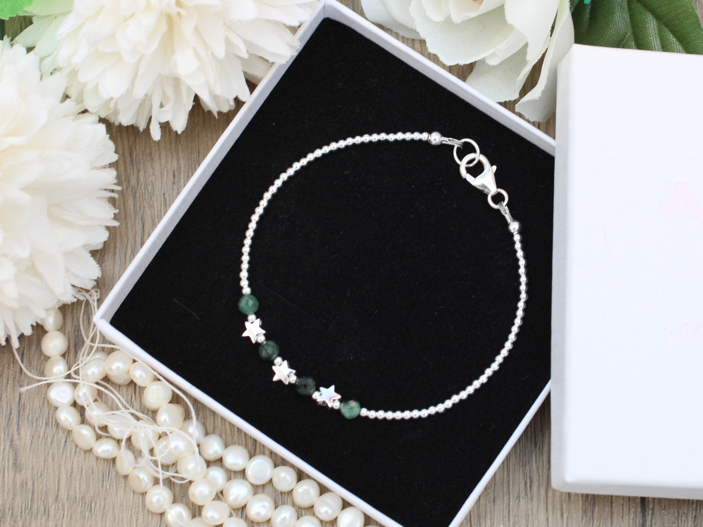 Silver star bracelet with emerald gemstones.