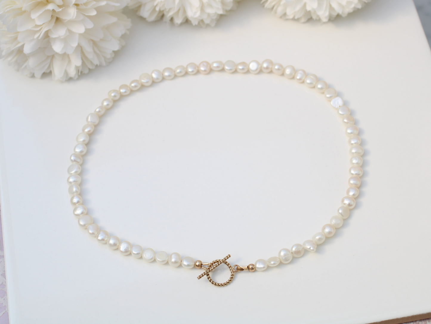 Pearl choker necklace with gold clasp.