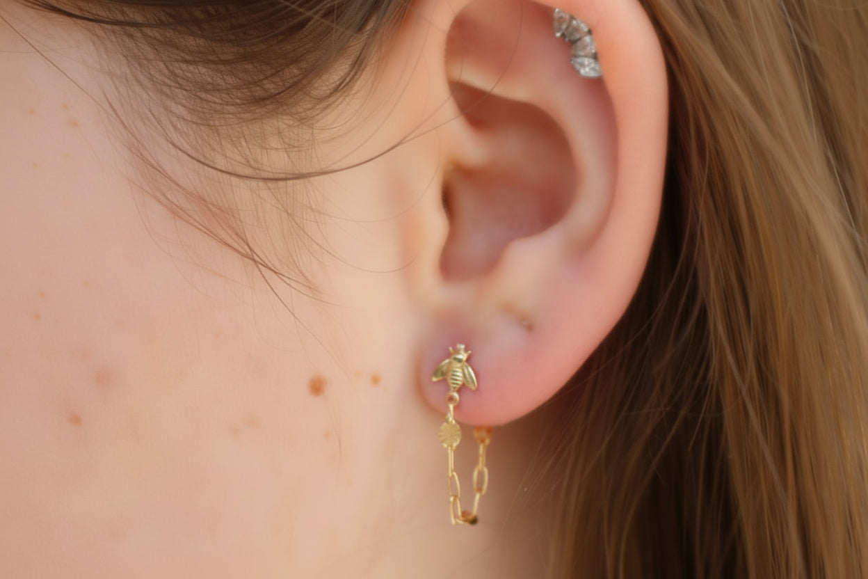 Close-up of an ear with a gold bee chain earring