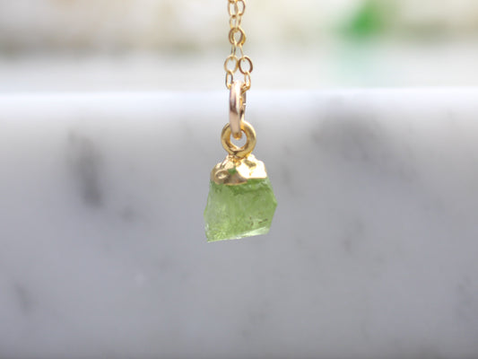 Raw peridot necklace in gold.
