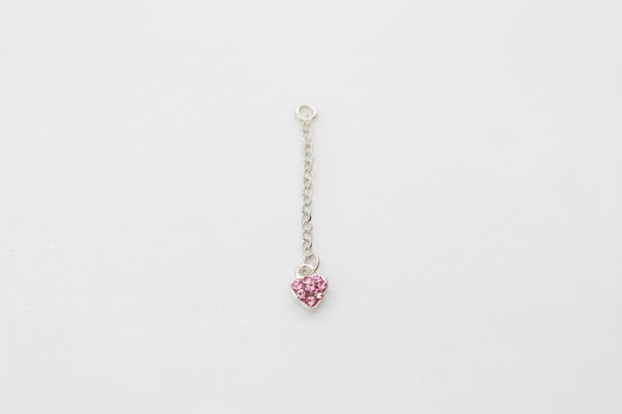 Pink heart-shaped pendant on a silver chain against a marble background