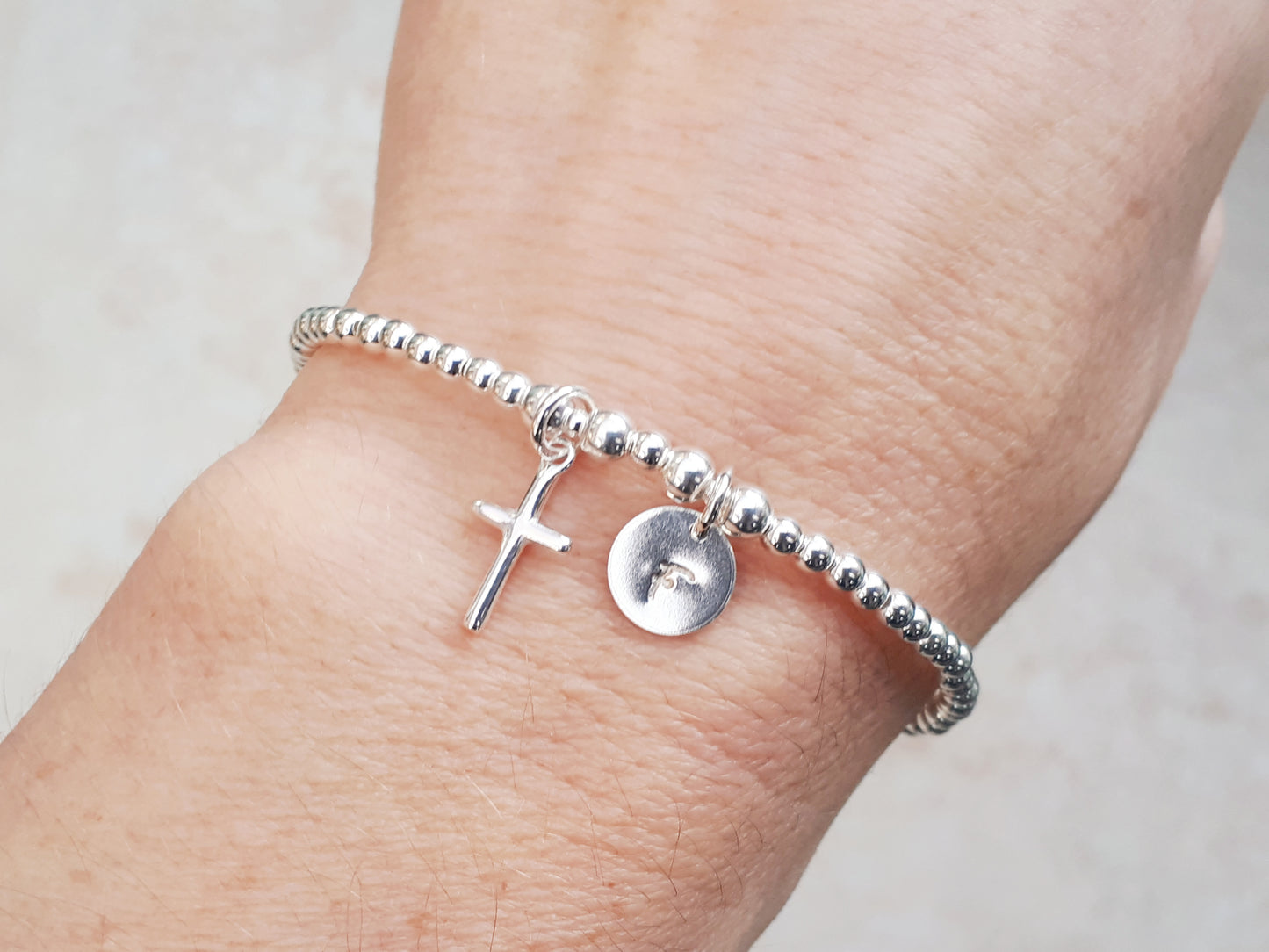 Cross charm bracelet with initial.