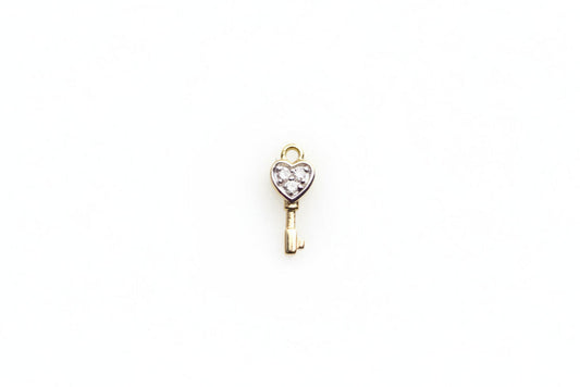 Gold key-shaped pendant with a heart on a light gray background