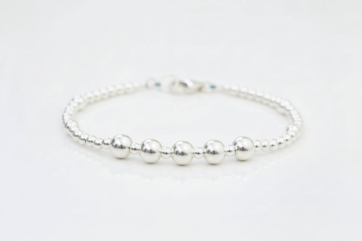 A sterling silver bead bracelet with a flower in the background, presented as a gift for a 50th birthday.
