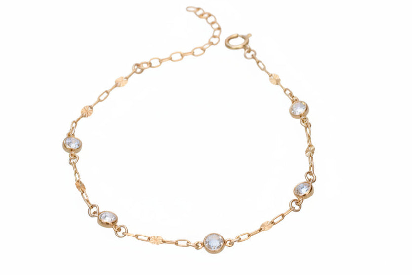 Gold bracelet with small crystals on a marble surface