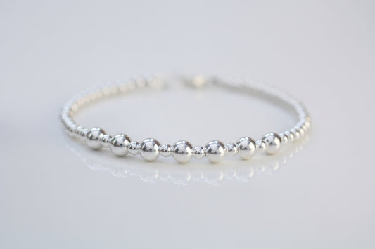 Silver beaded bracelet on a light gray background