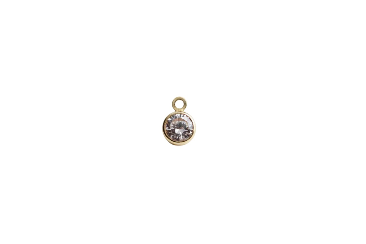 Gold pendant with a clear gemstone on a marble background