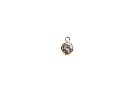 Gold pendant with a clear gemstone on a marble background