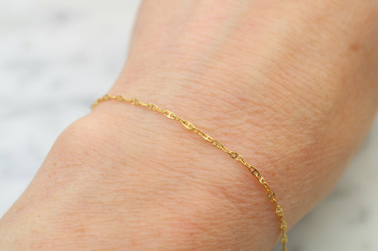 Gold bracelet on a person's wrist against a neutral background
