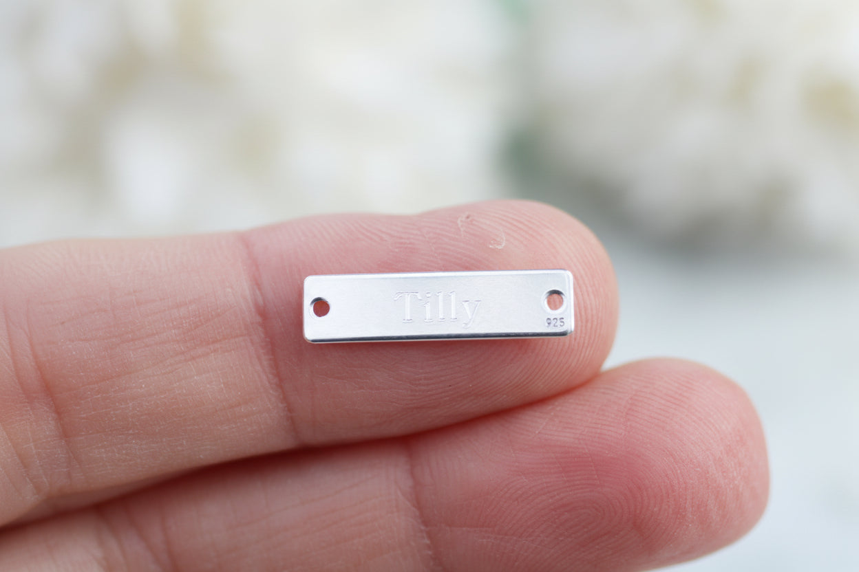 Engraved sterling silver rectangular tag.