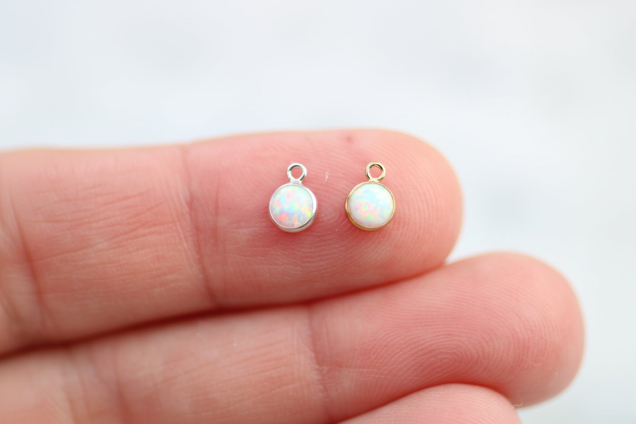 Opal earrings held between fingers on a light background