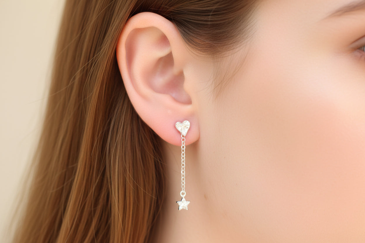 Close-up of a person wearing a silver heart-shaped earring with a star detail.
