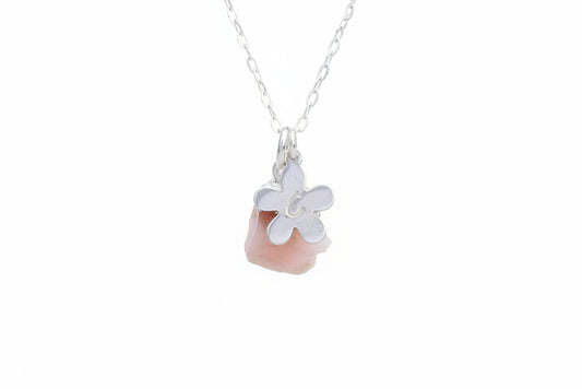 A silver chain necklace featuring a pendant with a white flower design layered over a smooth, polished pink stone, shown against a plain white background.