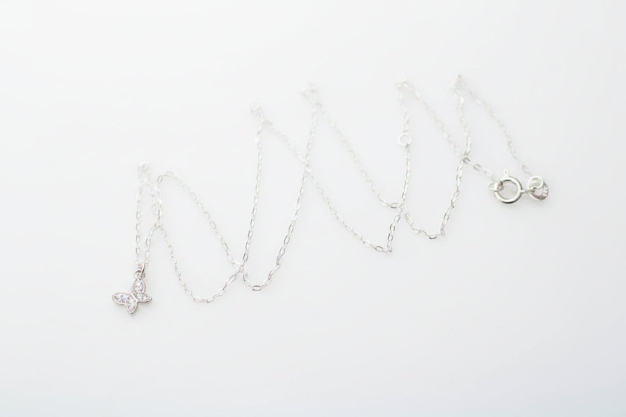 Silver necklace with a butterfly pendant on a marble surface
