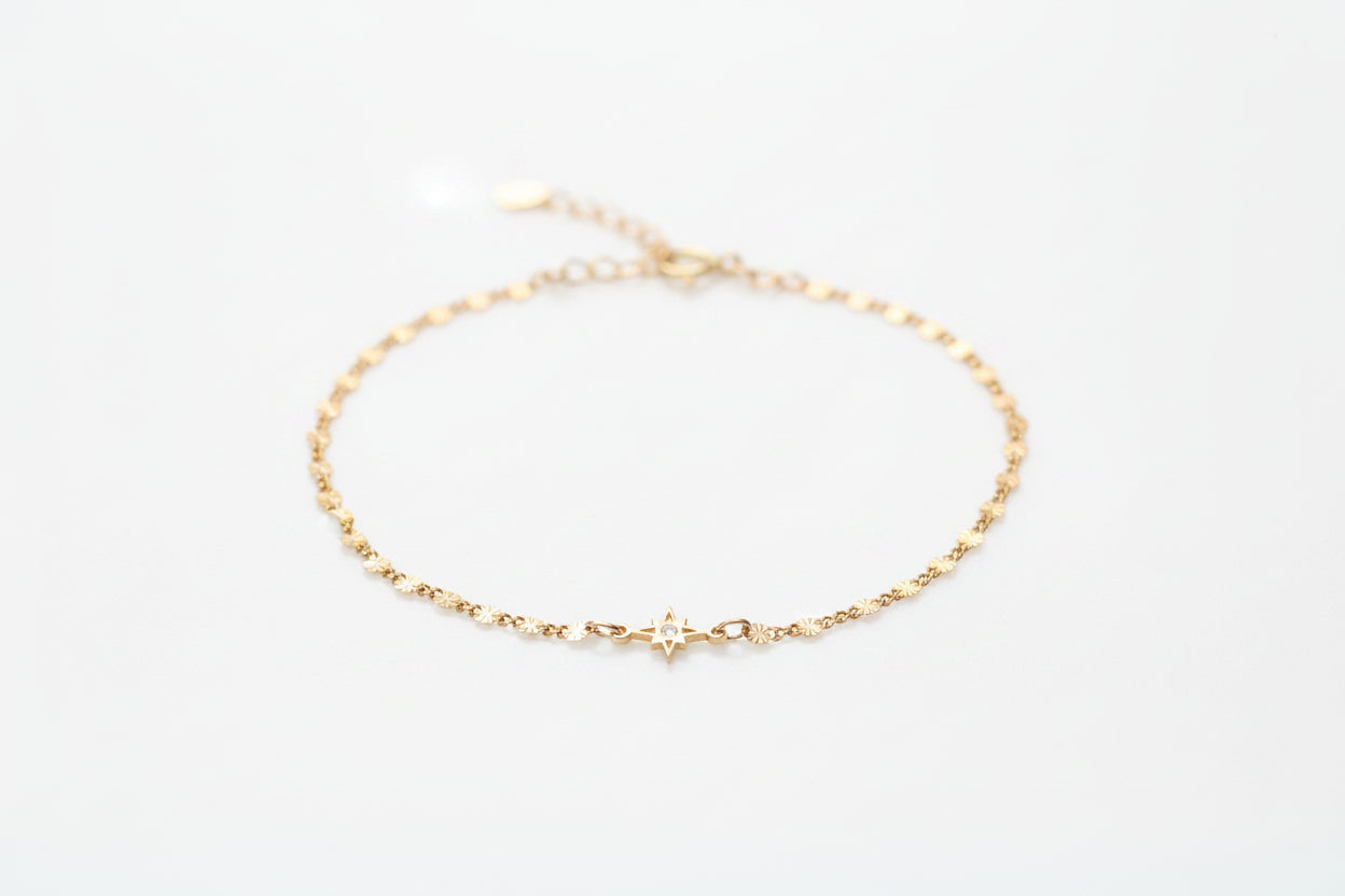 Gold bracelet with a star charm on a marble surface