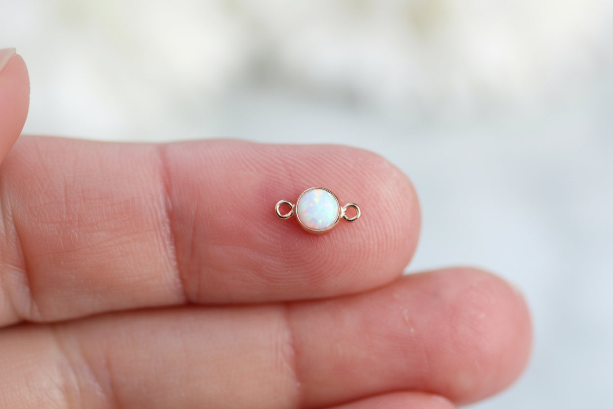 Small pearl earring on a person's finger with a blurred background
