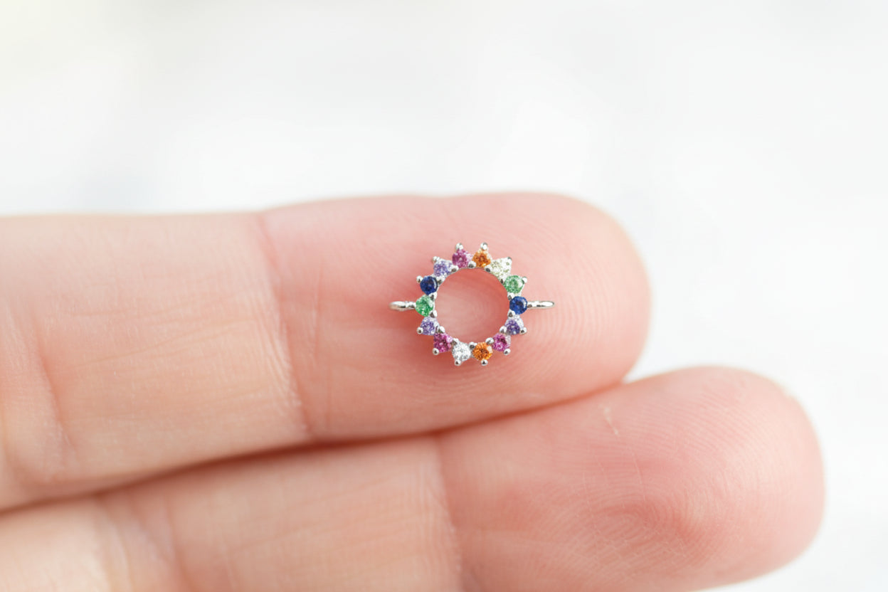 Small multicolored circular charm held between fingers against a white background