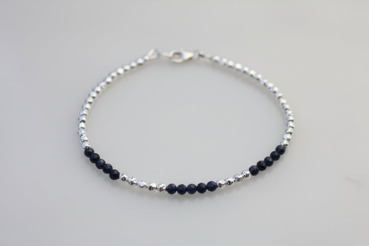 Silver bracelet with black beads on a marble surface
