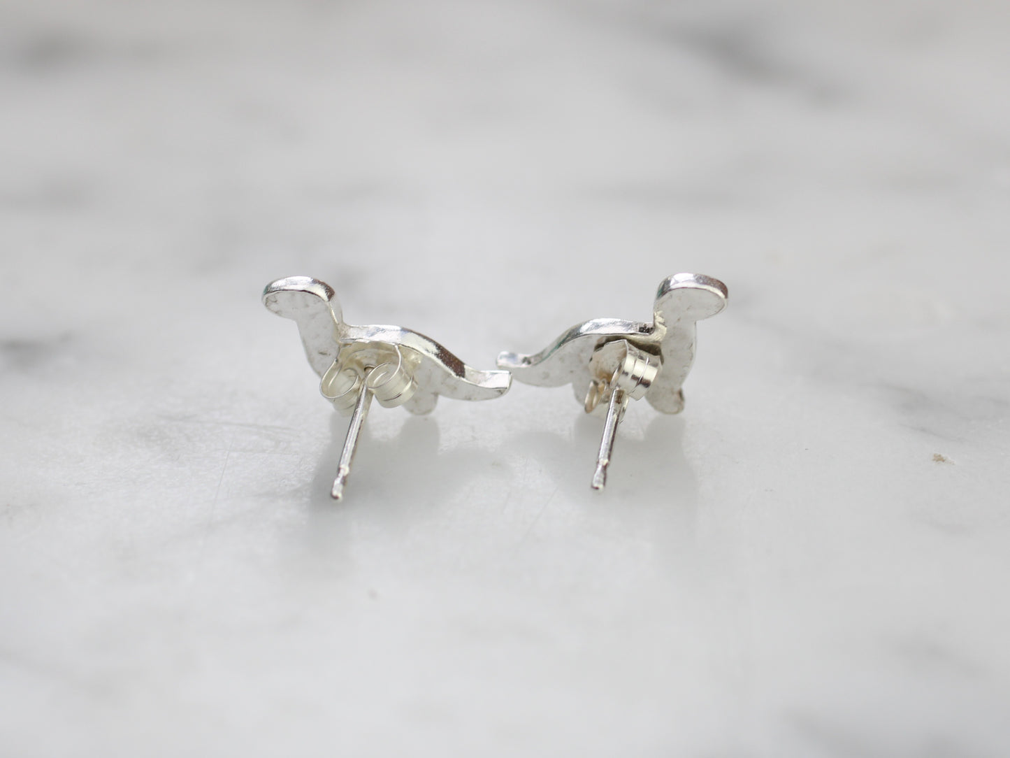 Diplodocus dinosaur stud earrings in silver.
