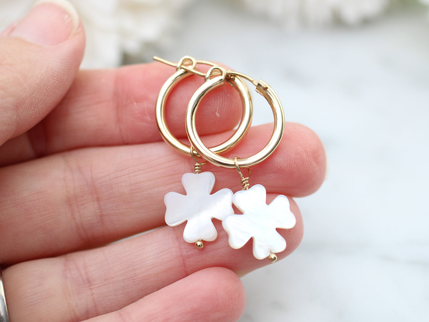 Four leaf clover hoop earrings in gold.