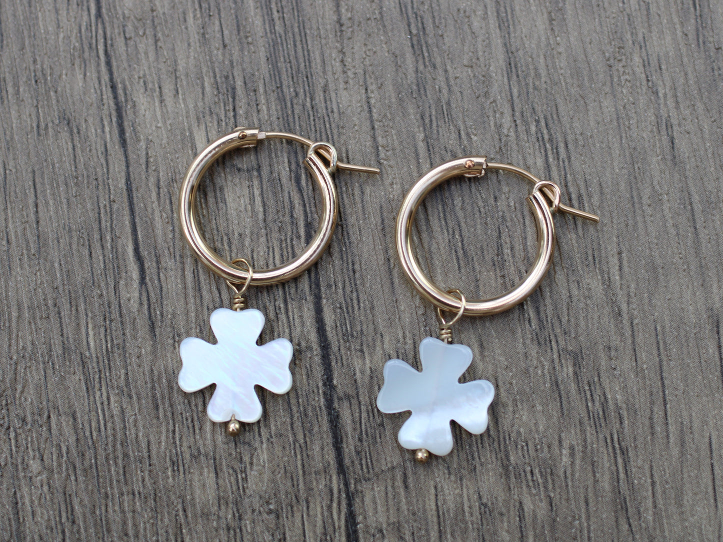Four leaf clover hoop earrings in gold.