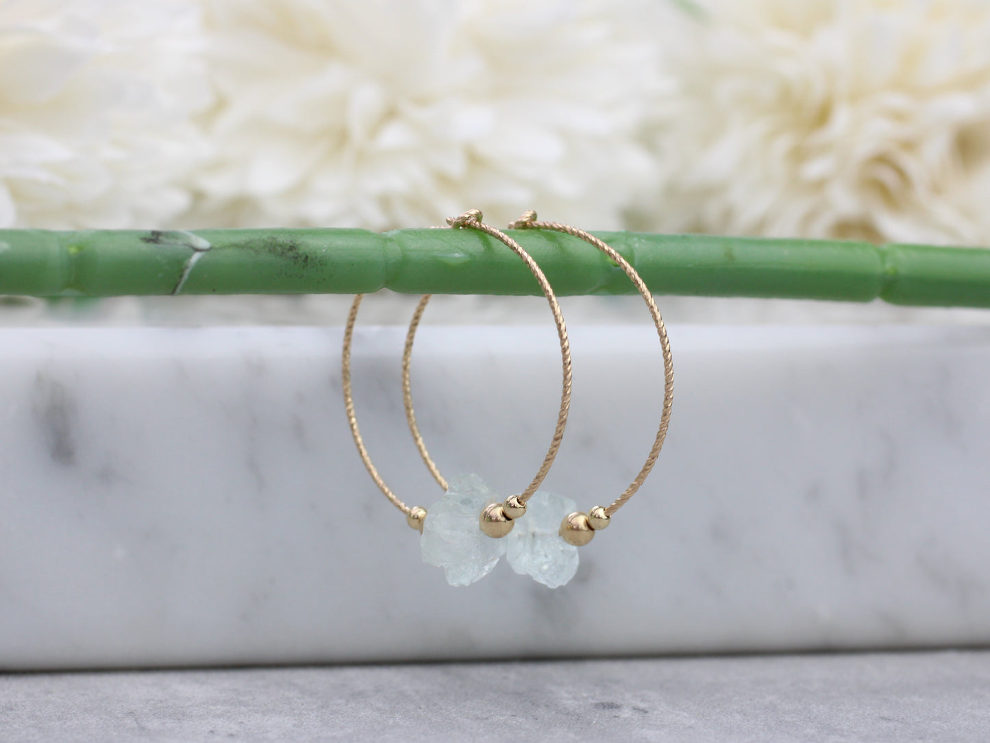 Raw aquamarine hoop earrings in gold.