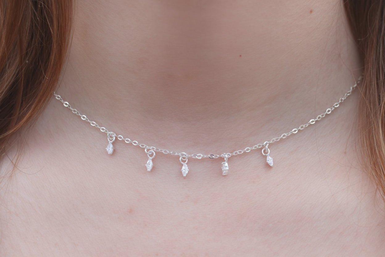 Silver necklace with small pendants on a person's neck