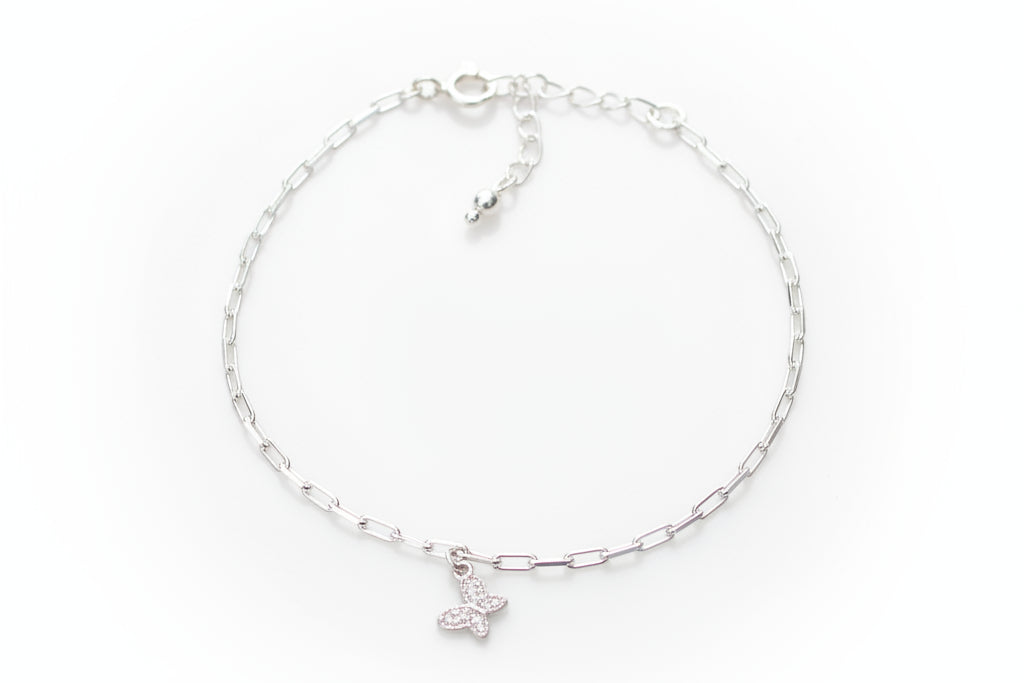 Silver bracelet with a butterfly charm on a marble surface