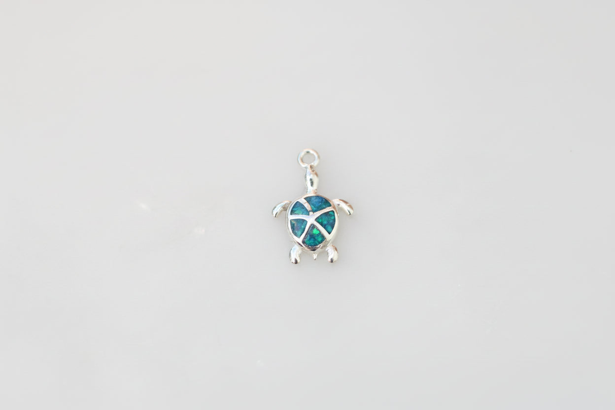 Turtle-shaped pendant with blue design on a marble background