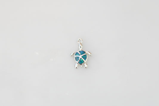 Turtle-shaped pendant with blue design on a marble background