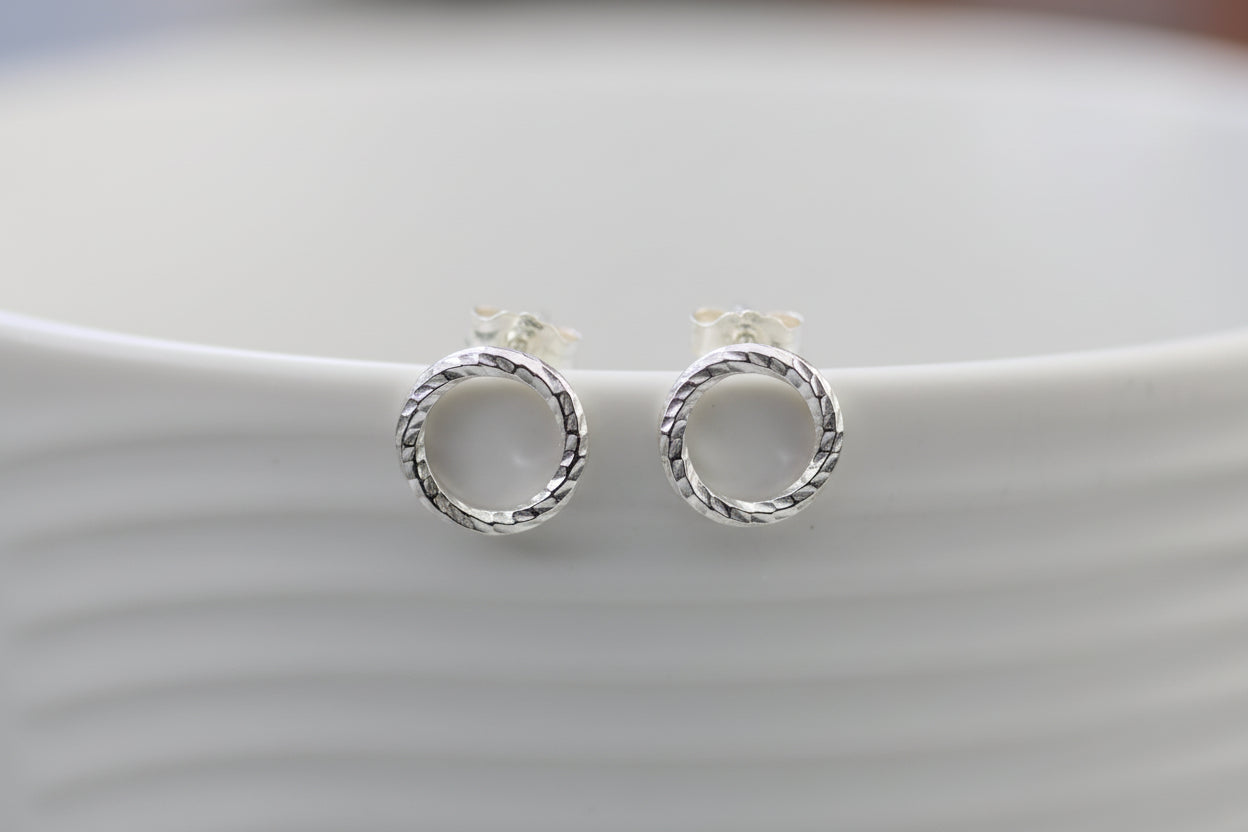 Pair of silver circular earrings on a light gray background