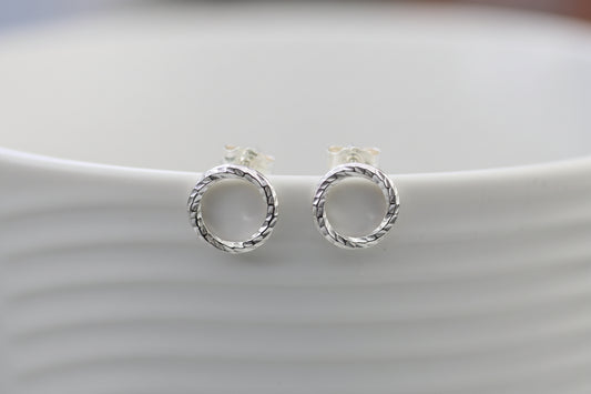 Pair of silver circular earrings on a light gray background