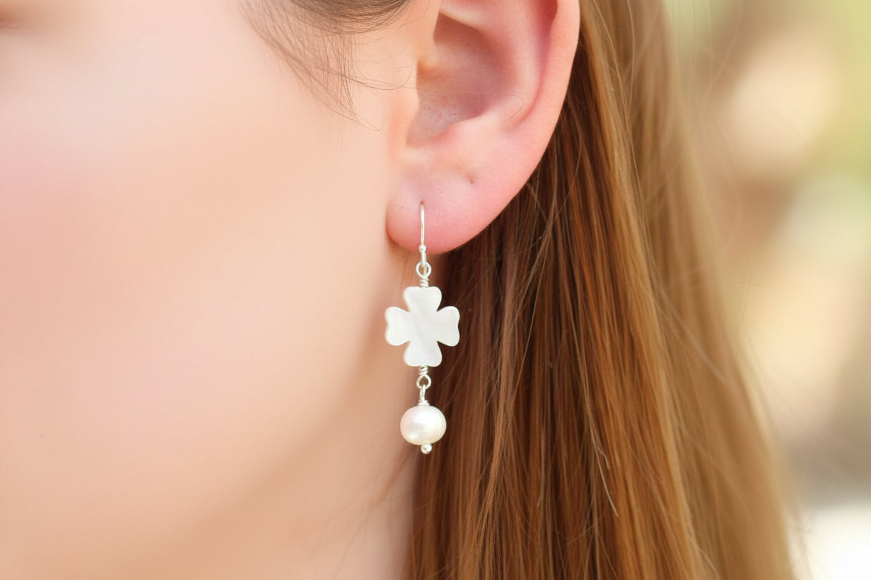Close-up of an ear wearing a floral earring with a blurred background
