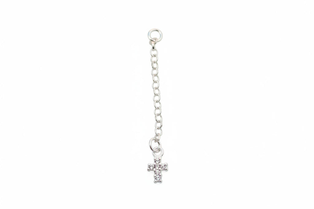 Silver chain with a small cross on a marble surface