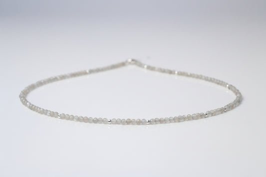 A grey moonstone choker necklace with sterling silver setting, featuring a series of round beads strung on a chain.