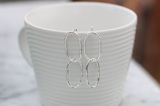 Silver earrings on a white textured cup