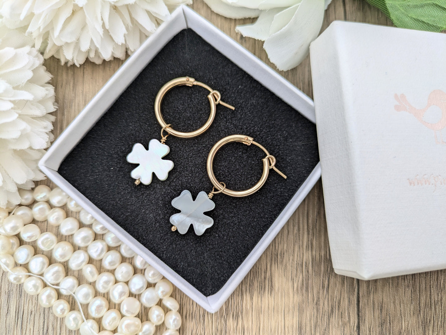 Four leaf clover hoop earrings in gold.
