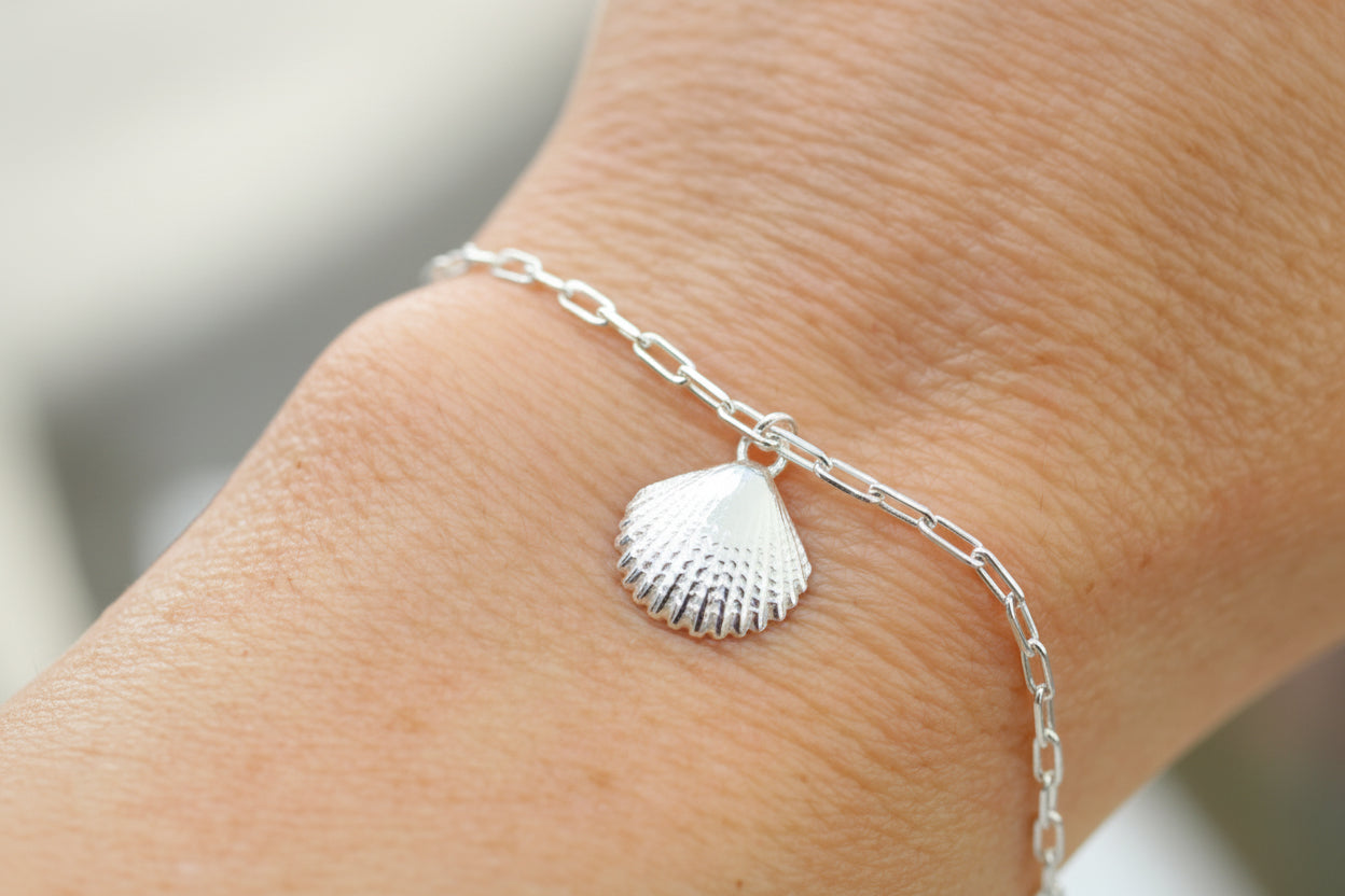 Silver shell braceket on a person's ankle with a blurred background