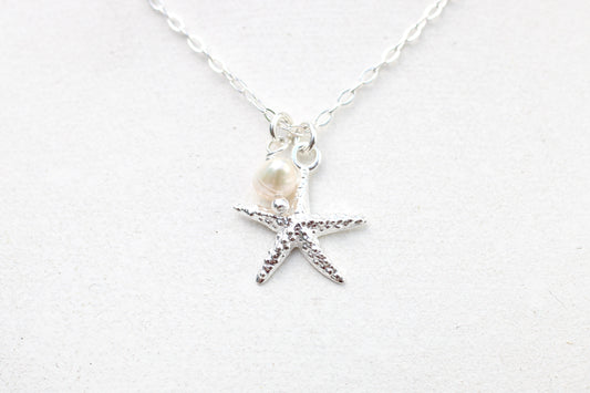 Necklace with starfish and pearl charm on a white background