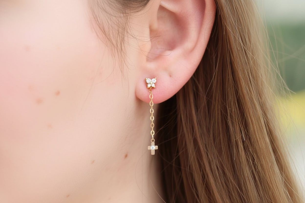 Close-up of an ear wearing a gold earring with a small butterfly charm.