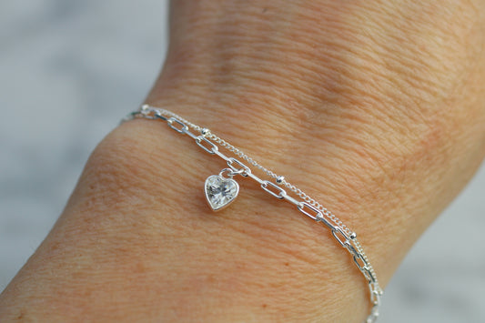 double chain bracelet with a heart charm on a wrist