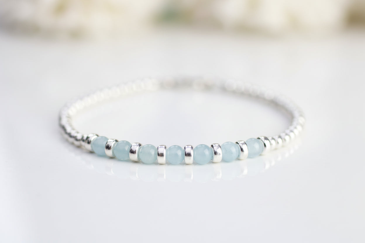 Beaded bracelet with light blue beads and silver accents on a white background