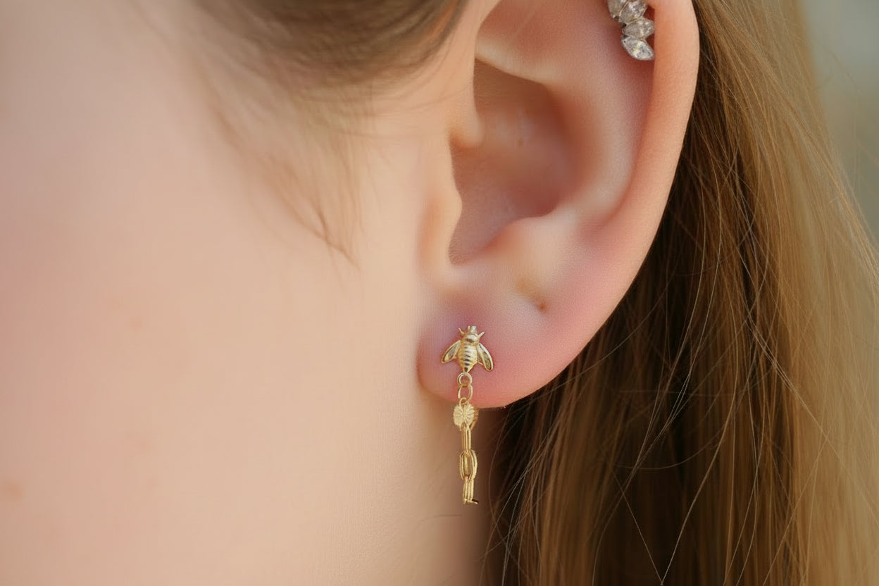 Close-up of a person wearing a gold bee-shaped earring.