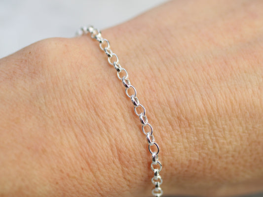 Silver chain bracelet on a wrist with a plain background