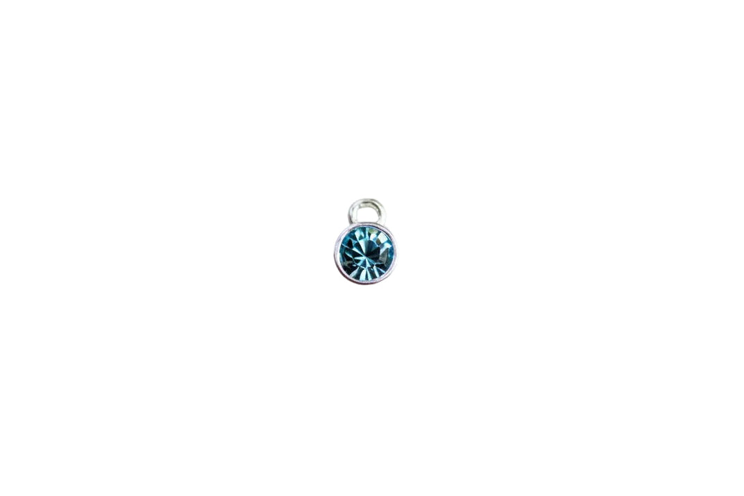 silver charm with blue crystal on a white surface